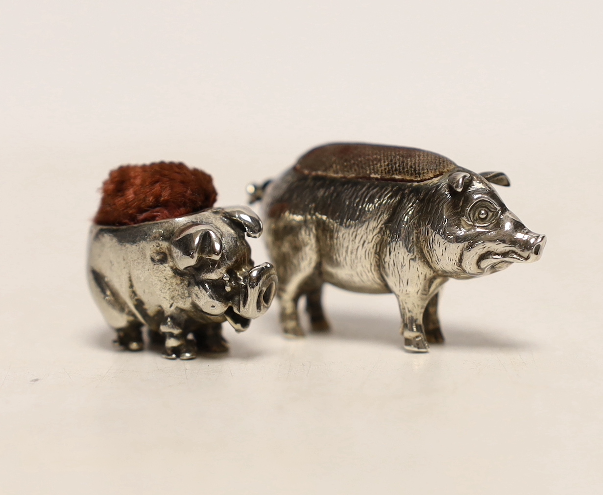 An Edwardian novelty silver pin cushion, modelled as a pig, Adie & Lovekin Ltd, Birmingham, 1909, 39mm and a later metal pig pin cushion.